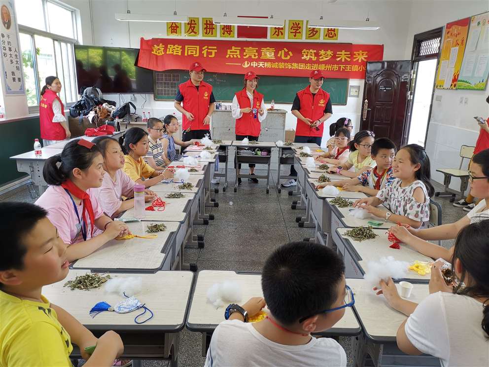 6月5日，中天精誠裝飾集團(tuán)的志愿者們在總經(jīng)理助理施江鋒的帶領(lǐng)下來到嵊州市下王鎮(zhèn)中心小學(xué)，為鄉(xiāng)村小學(xué)的孩子們帶去精彩的職業(yè)體驗(yàn)項(xiàng)目、端午禮物及溫暖的陪伴。  此次DO益行為孩子們帶來了飲品研發(fā)師、禁毒警察、美發(fā)設(shè)計(jì)師、魔術(shù)師、時(shí)裝設(shè)計(jì)師、郵遞員、印染師、百貨員的體驗(yàn)項(xiàng)目。活動現(xiàn)場，兩個(gè)多小時(shí)的體驗(yàn)，排隊(duì)等候、好奇、嘗試、探索與實(shí)踐，打破了志愿者與孩子們之間的陌生感，也圓了孩子們的職業(yè)夢。   臨近端午節(jié)，中天精誠裝飾的志愿者們還帶來了一項(xiàng)特色傳統(tǒng)文化活動——制作端午香囊， 佩香囊，是端午傳統(tǒng)習(xí)俗之一，香囊內(nèi)通常填充一些具有芳香開竅的中草藥，有清香、驅(qū)蟲、避瘟、防病等功能。這份“體驗(yàn)感十足”的端午節(jié)禮物贏得學(xué)生們的喜愛，在體驗(yàn)課上，學(xué)生們了解端午節(jié)的由來和習(xí)俗并親手制作端午香囊，把關(guān)心裝入香囊送給家人。  “人人可慈善、人人應(yīng)慈善”，付出、愛、公益、夢想，這些關(guān)鍵詞串起了志愿者與鄉(xiāng)村孩子的心，我們會一起努力，在成長的路上學(xué)會勇敢面對各種挑戰(zhàn)，最終實(shí)現(xiàn)自己的夢想。